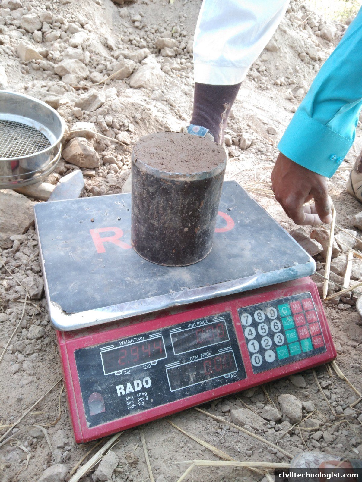Core cutter with soil sample on a digital weighing balance at site