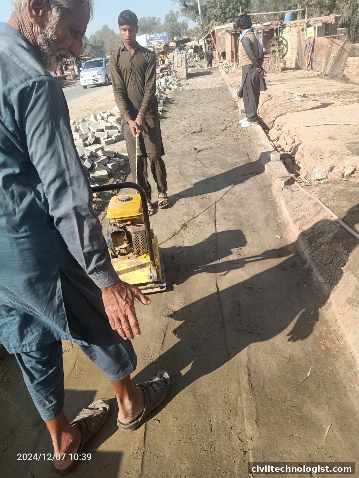 Plate compactor compacting soil in a confined area at site